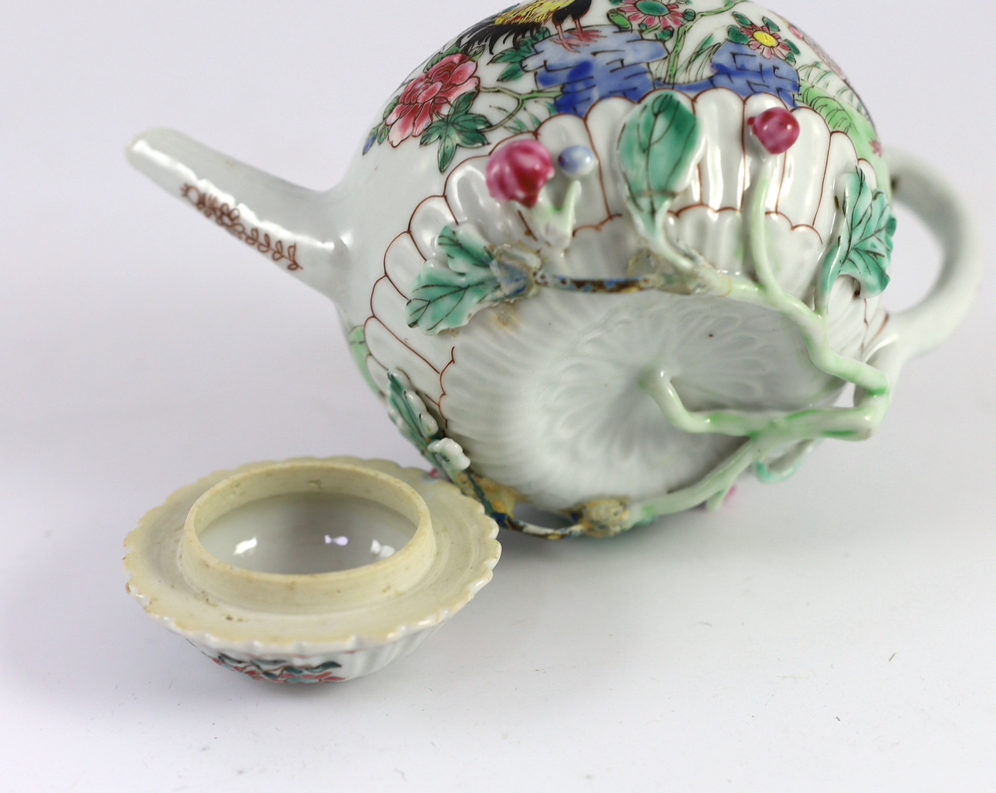 A Chinese famille rose chrysanthemum moulded teapot, early Qianlong period, painted with a cockerel amongst flowers, on a cage work base, 10 cms high